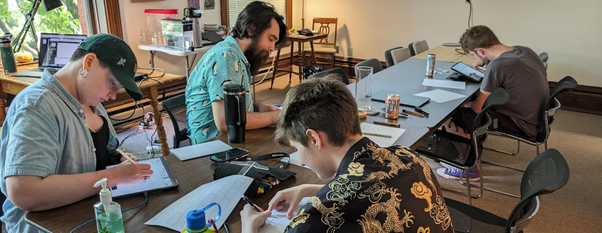 Men and women sitting around a table drawing storyboards